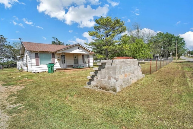 rear view of house with a porch, fence, and a yard