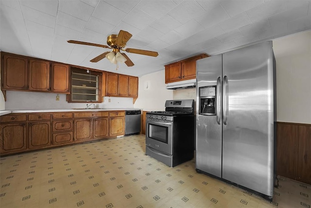 kitchen with a ceiling fan, a sink, under cabinet range hood, light floors, and stainless steel appliances