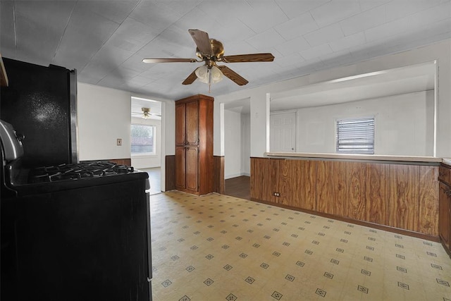 kitchen with gas stove, light floors, a ceiling fan, and brown cabinets