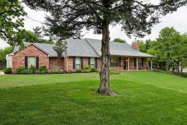 ranch-style house featuring a chimney, a front lawn, and brick siding