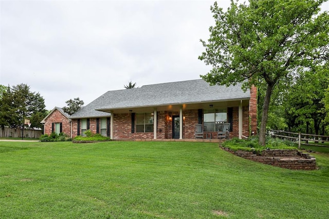 ranch-style house featuring covered porch, a front yard, brick siding, fence, and a shingled roof