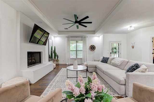 living room with a ceiling fan, a raised ceiling, dark wood-style flooring, and a wealth of natural light