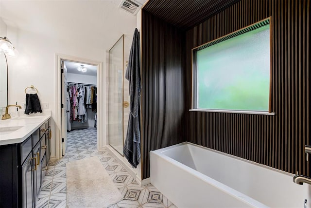 full bathroom featuring double vanity, a garden tub, visible vents, a stall shower, and a sink