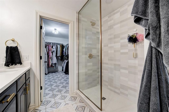 bathroom with vanity, a walk in closet, and a stall shower