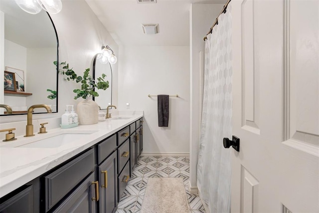 full bath featuring double vanity, a sink, baseboards, and visible vents