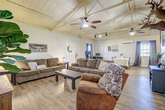 living area featuring an AC wall unit, lofted ceiling with beams, light wood-style floors, and ceiling fan