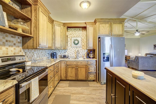kitchen featuring ceiling fan, appliances with stainless steel finishes, a sink, light wood-style flooring, and open floor plan