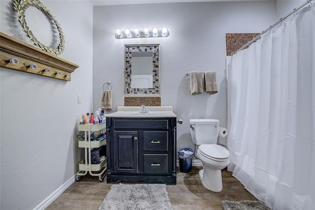 bathroom with vanity, wood finished floors, toilet, baseboards, and a shower with curtain