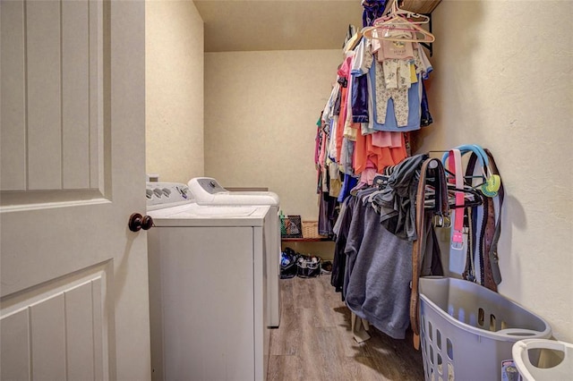 washroom featuring laundry area, a textured wall, wood finished floors, and washing machine and clothes dryer