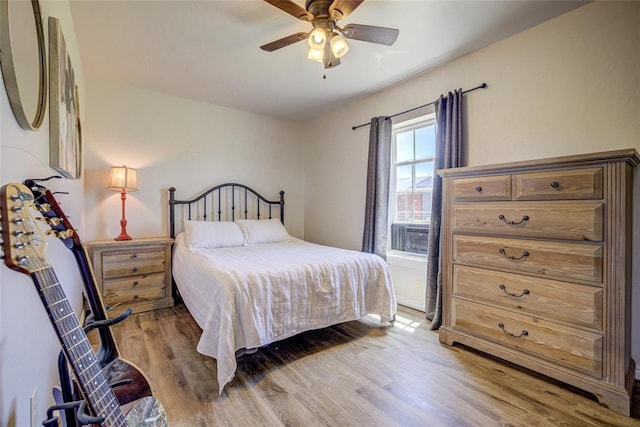 bedroom with a ceiling fan, light wood finished floors, and cooling unit