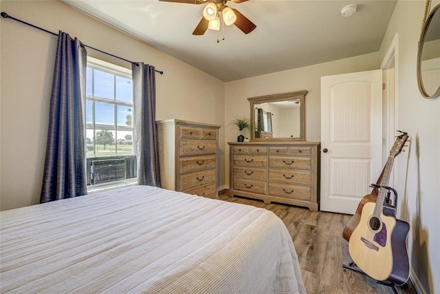 bedroom featuring ceiling fan, cooling unit, and light wood-type flooring