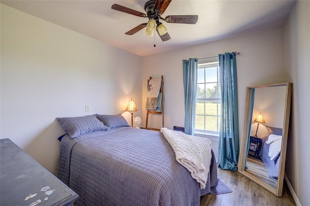 bedroom with a ceiling fan, baseboards, and wood finished floors