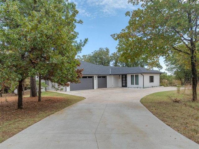 ranch-style home with a garage, concrete driveway, and roof with shingles