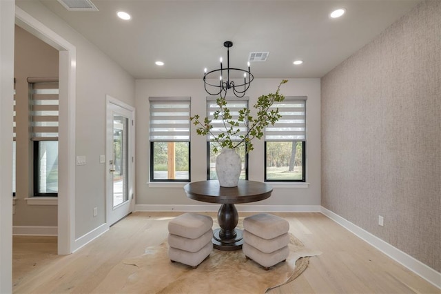 dining area featuring a healthy amount of sunlight, an inviting chandelier, light wood-style flooring, and visible vents