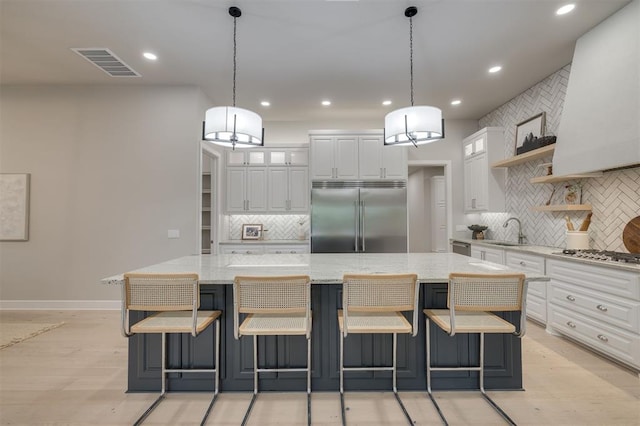 kitchen featuring visible vents, white cabinetry, a sink, backsplash, and stainless steel appliances
