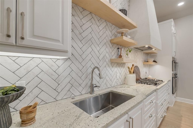 kitchen featuring stainless steel gas stovetop, open shelves, a sink, and tasteful backsplash