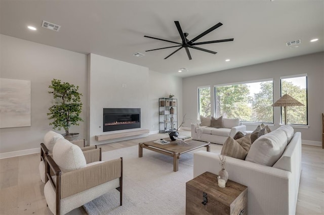 living area with visible vents, baseboards, and a glass covered fireplace