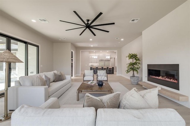 living area featuring visible vents, recessed lighting, light wood-style floors, and baseboards