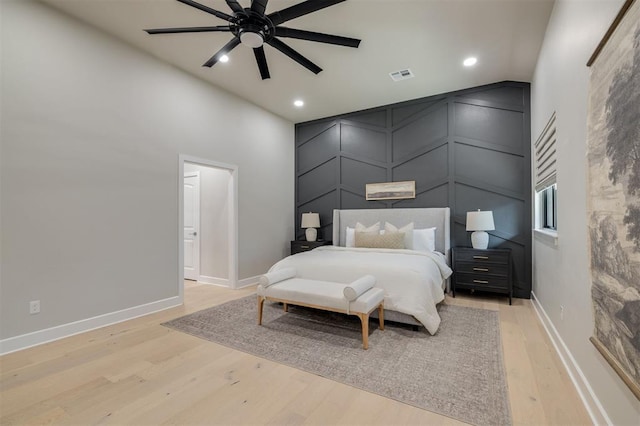 bedroom with visible vents, a decorative wall, high vaulted ceiling, recessed lighting, and light wood-type flooring