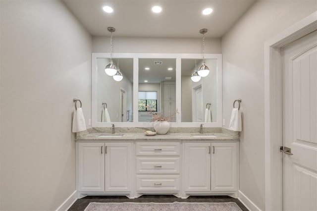 bathroom featuring double vanity, a sink, and recessed lighting