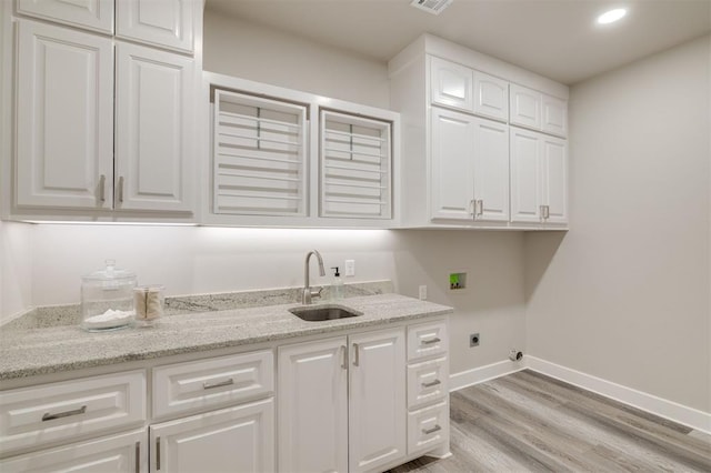 clothes washing area with washer hookup, electric dryer hookup, light wood-type flooring, cabinet space, and a sink