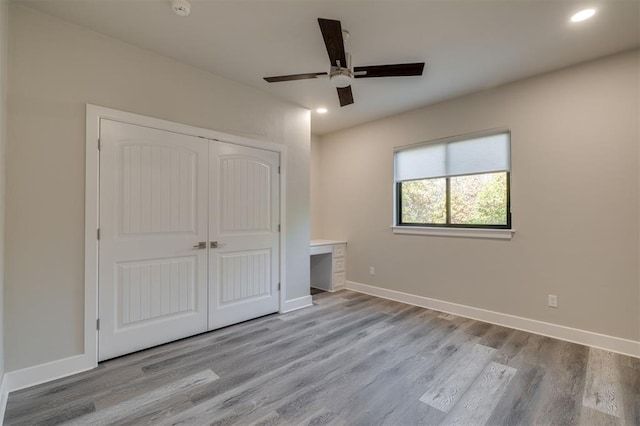 unfurnished bedroom with a closet, wood finished floors, baseboards, ceiling fan, and recessed lighting