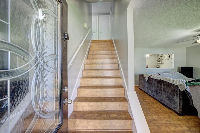 stairs featuring baseboards, a ceiling fan, a textured ceiling, and wood finished floors