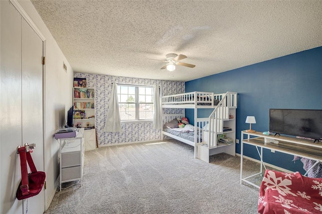 bedroom featuring carpet floors, a textured ceiling, ceiling fan, and wallpapered walls