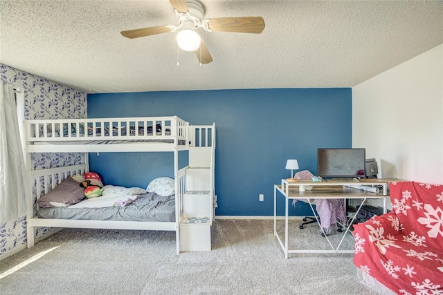 carpeted bedroom featuring a textured ceiling, wallpapered walls, and ceiling fan