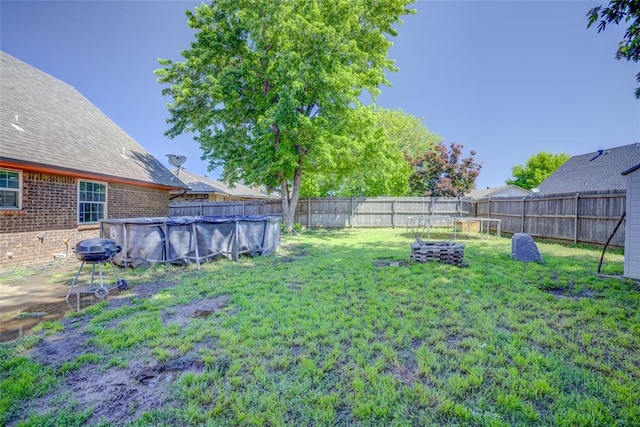 view of yard with a fenced in pool, a fenced backyard, and a trampoline