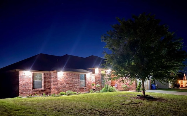 view of front of house featuring a yard, an attached garage, concrete driveway, and brick siding