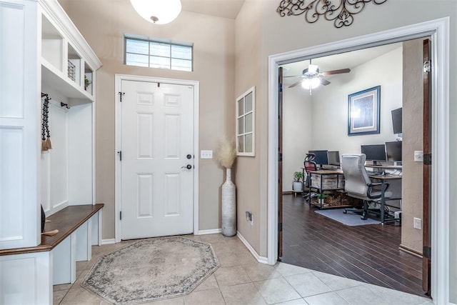 foyer with a ceiling fan, baseboards, and light tile patterned floors
