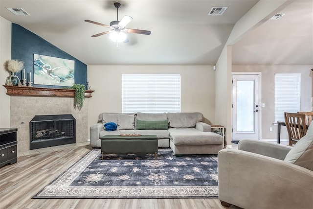 living room featuring ceiling fan, vaulted ceiling, wood finished floors, and visible vents