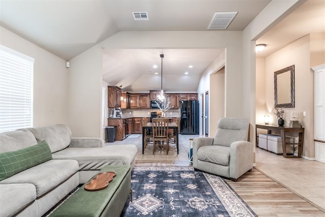 living area with vaulted ceiling, a chandelier, and visible vents