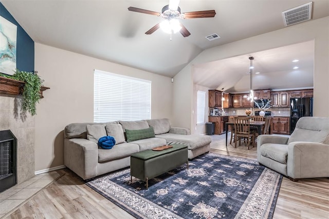 living area featuring a ceiling fan, visible vents, light wood-style flooring, and vaulted ceiling