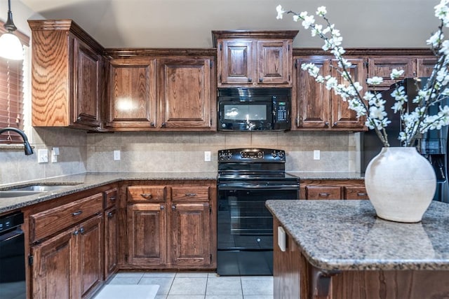 kitchen featuring a sink, tasteful backsplash, light stone countertops, and black appliances