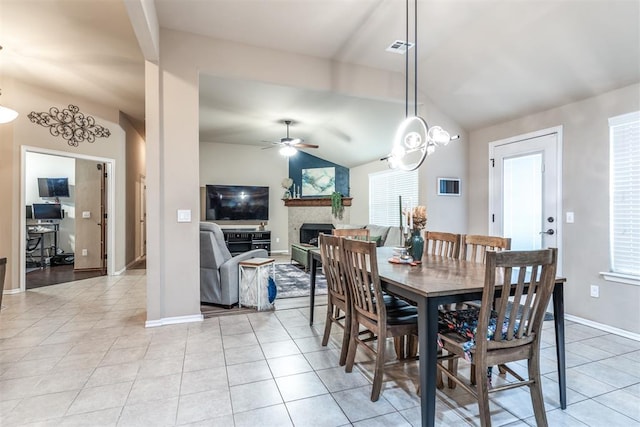 dining room with visible vents, a fireplace, a ceiling fan, light tile patterned floors, and vaulted ceiling