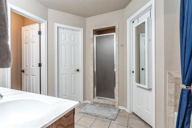 full bath with vanity, baseboards, tile patterned flooring, and a stall shower