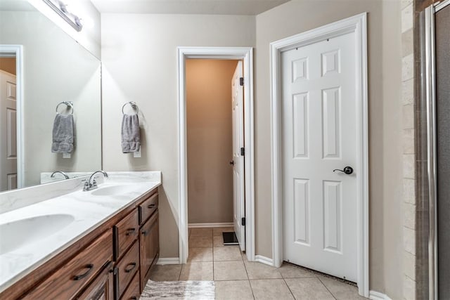 bathroom featuring baseboards, double vanity, tile patterned floors, and a sink