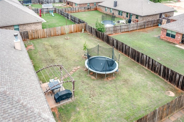 view of yard with a playground, a fenced backyard, and a trampoline