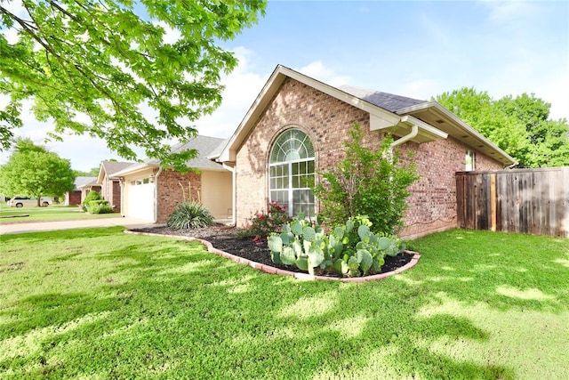 exterior space featuring brick siding, a garage, fence, and a yard