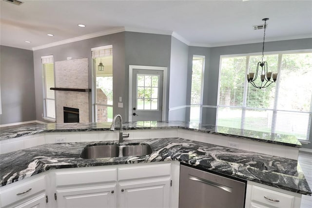kitchen with a sink, dishwasher, a chandelier, dark stone counters, and white cabinetry