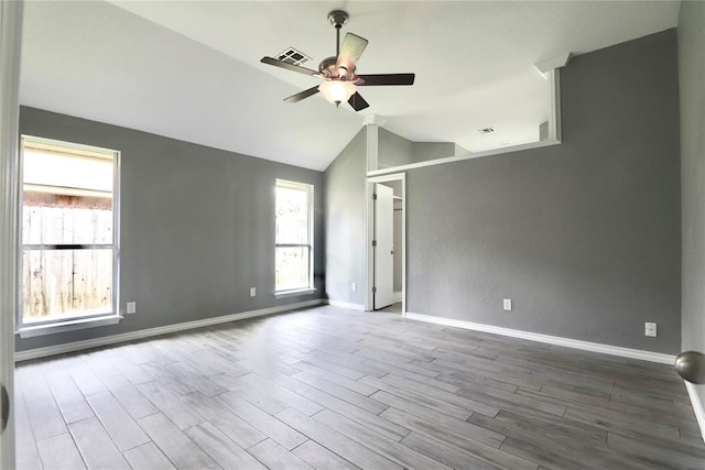 empty room featuring a ceiling fan, lofted ceiling, wood finished floors, and visible vents