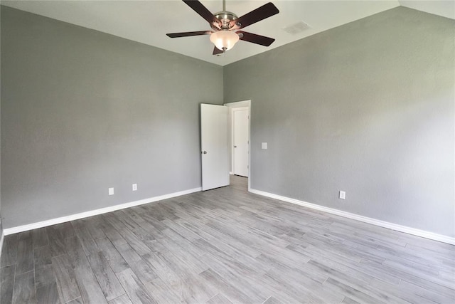 empty room with visible vents, wood finished floors, baseboards, a ceiling fan, and vaulted ceiling