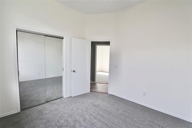 unfurnished bedroom featuring carpet floors, baseboards, and a closet