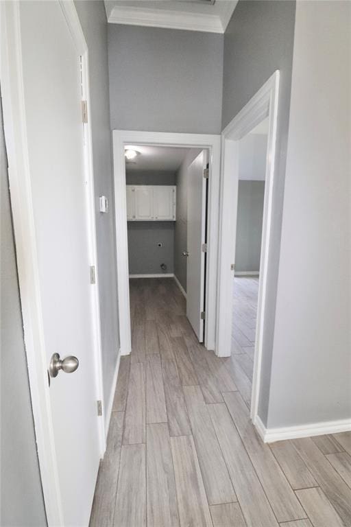 corridor with light wood-style floors, baseboards, and ornamental molding