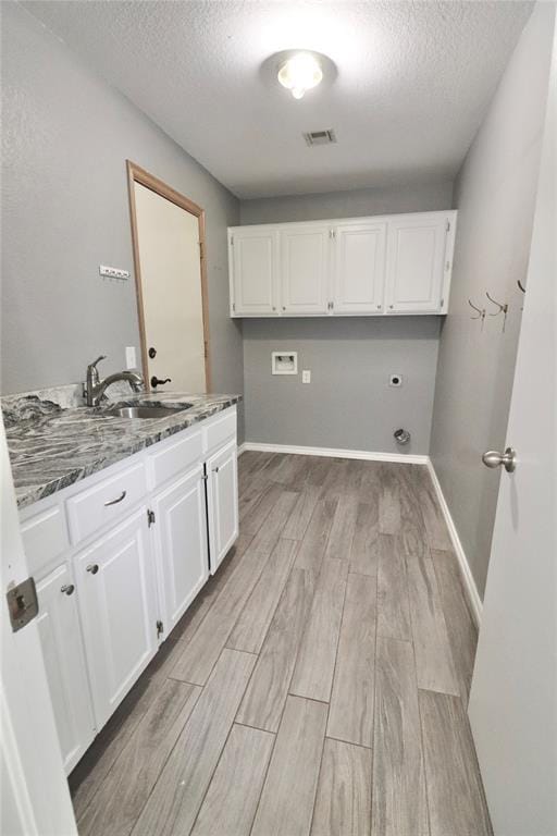 washroom featuring a sink, washer hookup, light wood-style flooring, and a textured ceiling