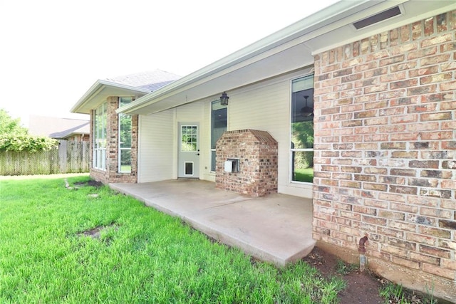 back of house with visible vents, a lawn, a patio area, brick siding, and fence