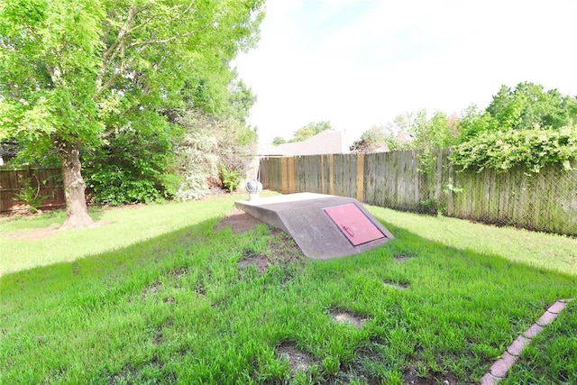 entry to storm shelter with a fenced backyard and a yard