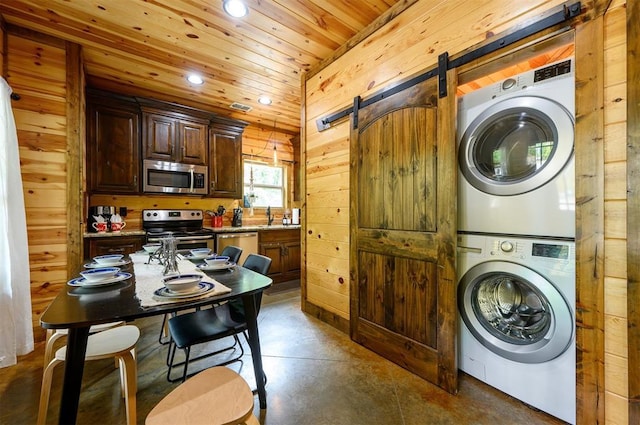 678 N State Highway 259a, Broken Bow, OK 74728 - laundry room featuring laundry area, a barn door, stacked washing maching and dryer, wooden walls, and recessed lighting